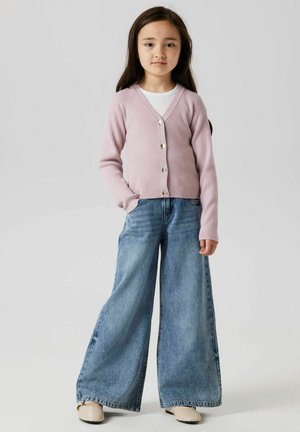 Cardigan ribbed rosa chiaro con scollo a V e cinque bottoni, abbinato a jeans in denim azzurro a gamba larga e scarpe beige.