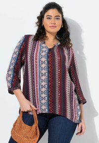 Blusa a maniche lunghe, con bottoni, caratterizzata da motivi intricati in bordeaux, blu navy e crema. Tessuto leggero con una vestibilità rilassata, abbinata a una borsa intrecciata.