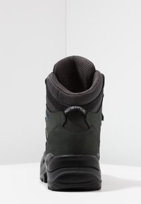 Bota de senderismo con parte superior de ante verde oscuro, cuello de malla y suela de goma negra texturizada. Incluye un talón reforzado y sistema de cordones.