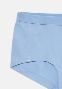 Jasnoniebieskie bawełniane slipy męskie z elastycznym pasem i widocznymi detalami przeszyć na białym tle.