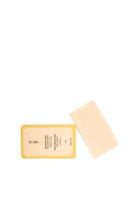 Barra di crema idratante per il viso in confezione gialla con testo bianco. Accanto alla barra c'è un sapone rettangolare di colore avorio con una texture liscia.