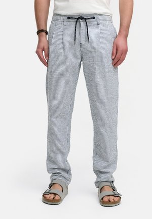 Pantalones a rayas de tela de algodón en azul y blanco con cinturilla elástica y cordón. Llevados con sandalias grises, mostrando un ajuste relajado.