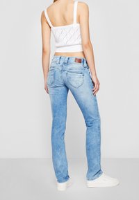 Ljusblå jeans med en urtvättad effekt, med en figurnära design, två bakfickor och en brun logotypplatta på midjebandet.