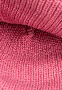 Textured pink knit fabric with fine ribbing, showcasing a soft, warm appearance and slight fuzzy detail throughout the surface.