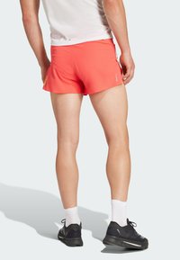 Korte sportieve shorts in helder koraal, gemaakt van lichtgewicht stof. Kenmerkt zich door een strak ontwerp met zijstrepen en een flexibele tailleband.