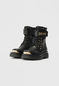 Botine negre din piele cu accente aurii, дизайн cu şireturi, fermoar lateral și bandă cu logo-ul „Justcavalli”. Talpă groasă, texturată.