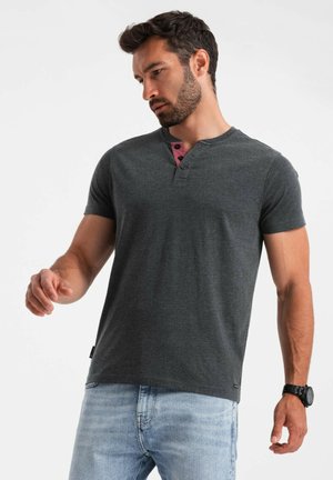 Camiseta de manga corta en gris oscuro con escote tipo henley y dos botones, que presenta un acento en burdeos contrastante cerca del cuello.