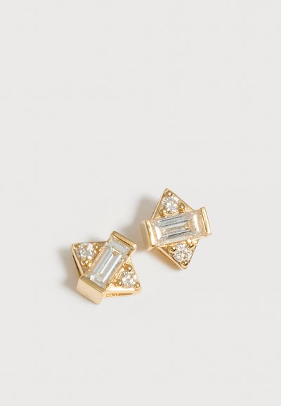 Boucles d'oreilles triangulaires en or avec trois petits cristaux ronds et un grand cristal rectangulaire au centre sur fond blanc.
