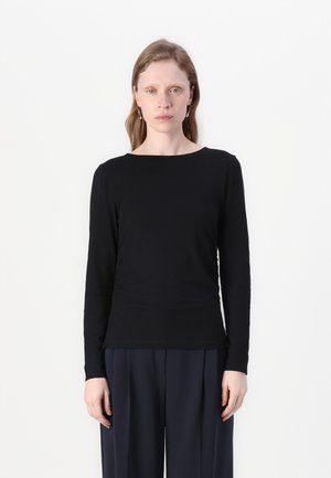 Black long-sleeve shirt with a round neckline; made from smooth fabric; fitted shape; worn with loose navy pants.