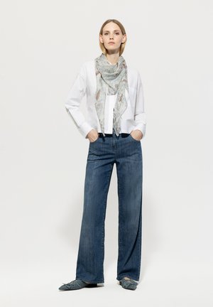 Weißes Hemd mit Knöpfen, leichter floral gemusterter Schal, weit geschnittene Jeanshosen und blaue Ballerinas. Das Outfit zeichnet sich durch lässige, moderne Designelemente aus.