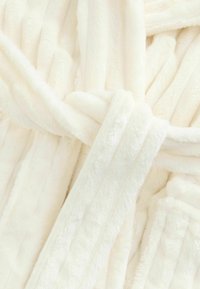 White plush robe featuring soft, fluffy texture with a tied belt, showcasing a smooth, even surface and subtle vertical stripes.