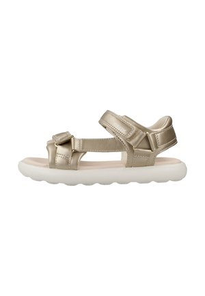 Sandalias metálicas doradas con dos correas ajustables, un tobillo acolchado y una suela blanca acolchada con un patrón en forma de ola.