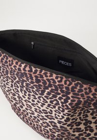 Lāču raksta auduma soma ar melnu iekšpusi, ar rāvējslēdzēja aizdari un iekšējo kabatu. Zīmola etiķete "PIECES" redzama iekšpusē.