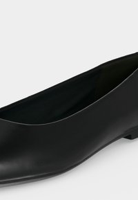 Γυναικείο μαύρο δερμάτινο παπούτσι με χαμηλό τακούνι και ελαφρώς τετράγωνη μύτη, απεικονίζεται από πλάγια γωνιακή όψη.
