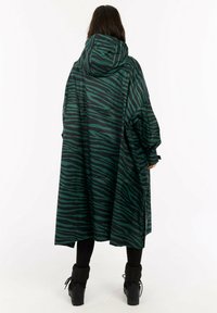 Przeciwwiatrowa kurtka z kapturem w ciemnozielonym kolorze z czarnymi paskami tygrysa. Charakteryzuje się luźnym krojem, długimi rękawami oraz gładką, wodoodporną fakturą.
