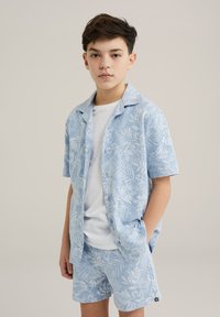 Set composto da camicia leggera blu cielo e pantaloni corti con motivo a foglie tropicali. Realizzato in tessuto morbido, con maniche corte e chiusura a bottoni.