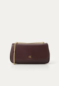 Geantă de umăr din piele burgundă cu un breloc din aur, având margini cusute și un logo embosat pe față. Design compact și rectangular.