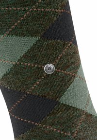 Calza di maglia con motivo a diamante in verde, nero e marrone. Presenta cuciture arancioni a contrasto e un accento con logo argento.