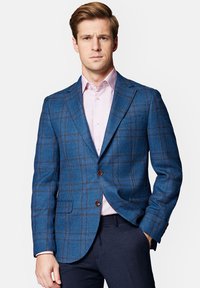 Niebieska marynarka w kratę, wykonana z wełny, z brązowymi akcentami, wyłogami i dwoma przednimi kieszeniami; nałożona na jasnoróżową koszulę.