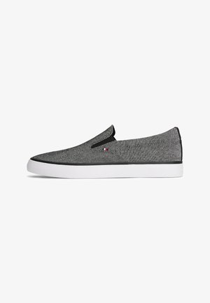 Grauer Slip-On-Sneaker mit weißer Gummisohle und kleinem rot-weiß-blauem Logo an der Seite, vor weißem Hintergrund.