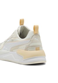 Beige en crème sportieve schoen met een getextureerde suede en mesh bovenwerk, witte tussenzool en een lichtbruine zool. Voorzien van een hiel-lussen.