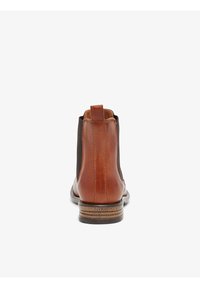 Botas chelsea de cuero marrón con paneles laterales elásticos, una lengüeta y una suela de goma texturizada. Acabado suave con lados en contraste.
