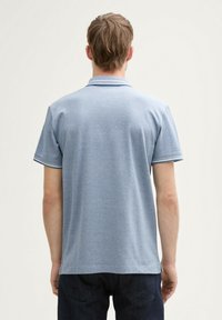 Lichtblauw polo shirt van katoen. Korte mouwen, geribde kraag met contrasterende afwerking, en een casual pasvorm. Alleen achteraanzicht.