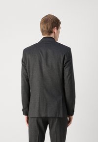 Donkergrijs op maat gemaakt blazer met een gladde textuur, enkele knoopsluiting en subtiele stikdetails, ontworpen voor een moderne pasvorm.