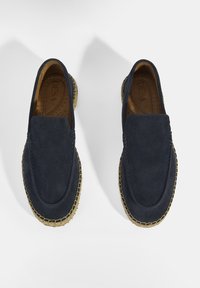 Navy suède instappers met een ronde neus en een geweven jute zool. Voorzien van stiksels langs de randen en een gladde textuur.