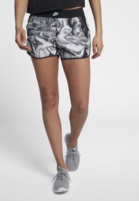 Nike šortky s černobílým mramorovým vzorem, elastickým pasem a kontrastním černým lemem; v kombinaci s lehkými šedými teniskami.