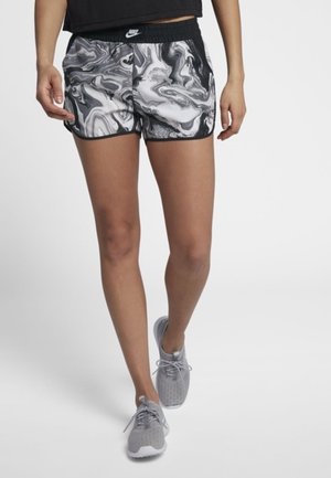 Shorts Nike avec un motif marbré noir et blanc, ceinture élastique et bord noir contrastant ; associés à des baskets grises légères.