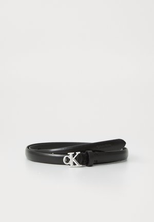 Cintura in pelle nera avvolta con fibbia argento "cK" e marchio in rilievo "Calvin Klein" all'estremità su uno sfondo bianco.