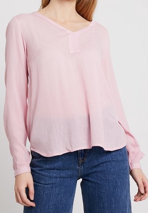 Blouse rose clair à manches longues avec un col en V et des détails à boutons au niveau du cou ; fabriquée en tissu texturé et léger ; coupe décontractée.