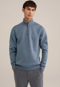 Herrtröja i blått, med polokrage och halvdragkedja. Tillverkad av mjukt material med ribbade manschetter och nederkant.