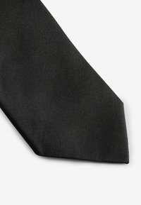 Crna kravata izrađena od teksturiranog materijala, s klasičnim uskim oblikom i šiljastim krajem. Glatka površina s suptilnim detaljima.