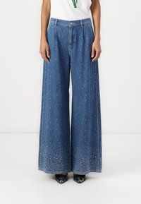 Wijd gesneden denim jeans met een lichte wassing, voorzien van verspreide versieringen dicht bij de zoom, en een klassiek vijf-pocket ontwerp.