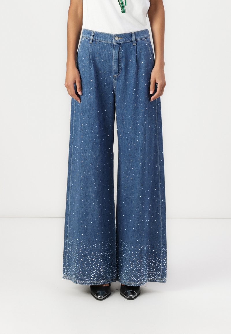 Wijd gesneden denim jeans met een lichte wassing, voorzien van verspreide versieringen dicht bij de zoom, en een klassiek vijf-pocket ontwerp.