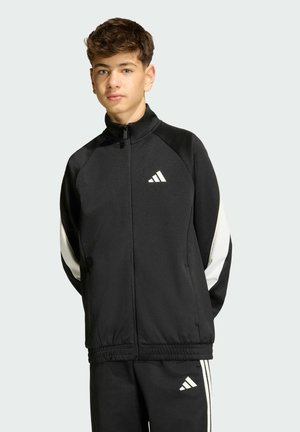 Black zip-up jacket made of soft fabric, featuring white accents on sleeves and a small white logo on the chest. Elastic waistband at the bottom.