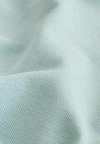 Tissu bleu clair texturé avec un petit motif tissé et de légers plis créant des ombres et des reflets doux.