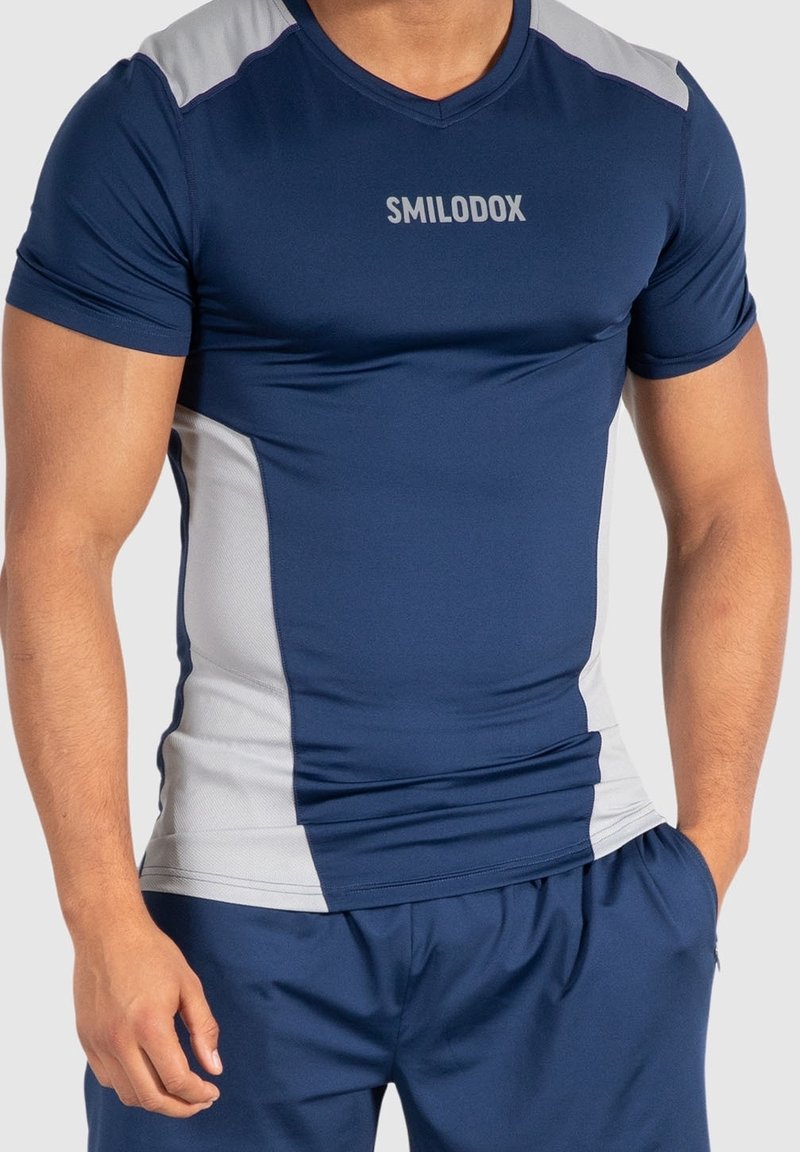 Námořnická modrá sportovní tričko s krátkým rukávem, s šedými bočními panely a logem "SMILODOX" na hrudi. Vyrobeno z pružného, lehkého materiálu.