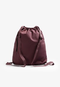 Mochila de cordón en tejido burdeos, con correas ajustables y una superficie texturizada. Incluye un bolsillo con cremallera lateral para accesorios.