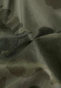 Maskovacia látka v tmavozelených odtieňoch, ktorá má textúrovaný povrch s rôznymi odtieňmi a hladkým, plynulým vzhľadom.