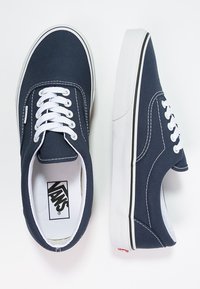 Marine lerret sneakers med hvite snører, hvite gummisåler og svarte detaljer. Har en rund tå og et logomerke innvendig.