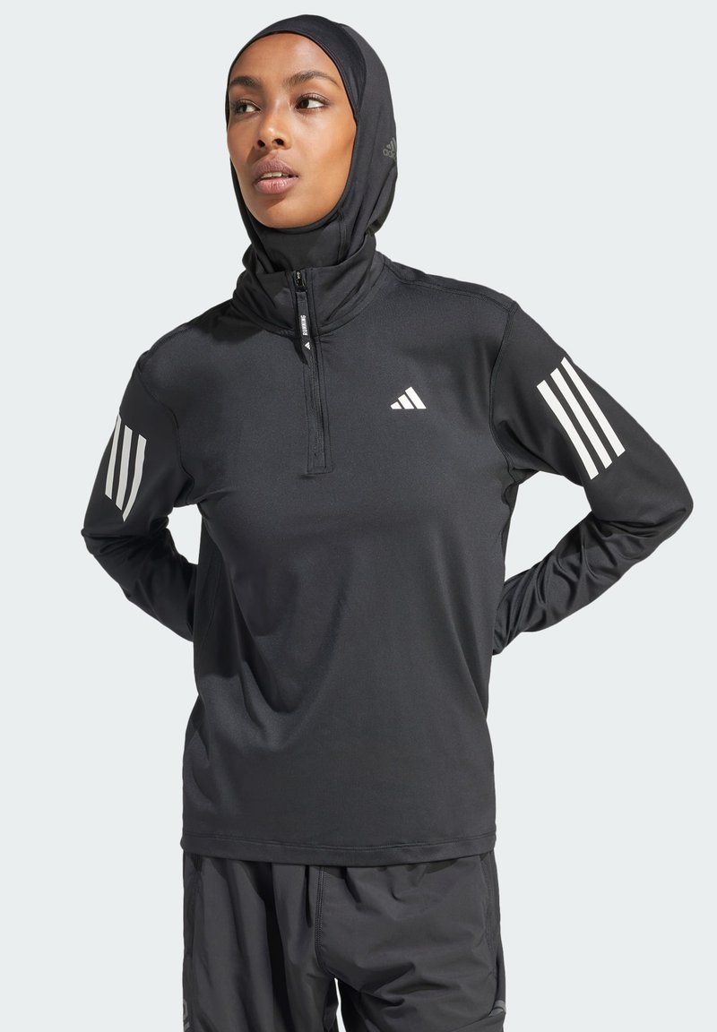 Top atletico nero con colletto a metà zip, maniche lunghe e design a tre righe bianche sulle spalle. Tessuto liscio e leggero con una vestibilità aderente.