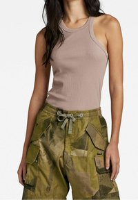 Top in cotone a coste color marrone chiaro abbinato a pantaloni cargo in camouflage verde, dotati di più tasche, cintura con cordoncino e tessuto testurizzato.