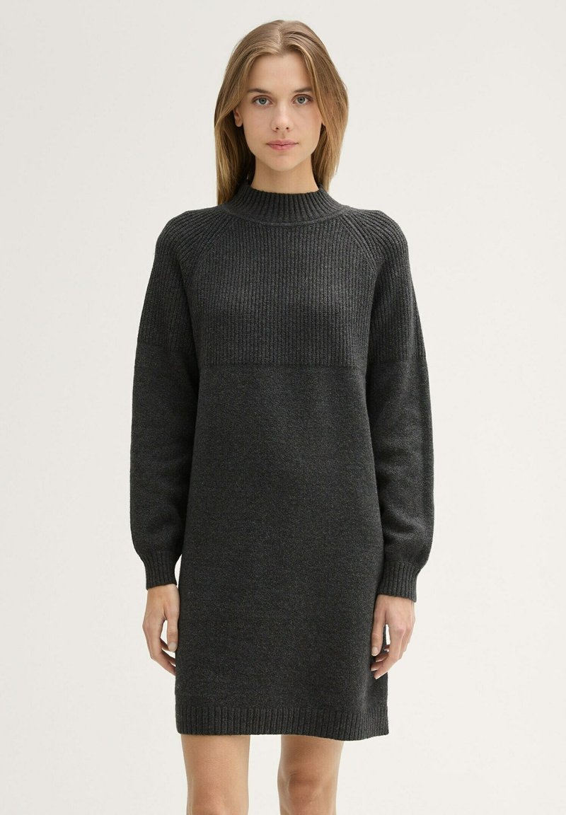 Abito in maglia grigia scura con collo alto, texture a coste sulla parte superiore e sezione inferiore liscia. Maniche lunghe che si stringono ai polsi.