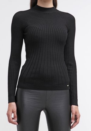 Suéter negro de punto acanalado con cuello alto, diseño ajustado, mangas largas y sutil detalle del logo en la cintura, combinado con pantalones negros.