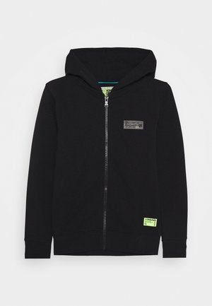 Sort lynlåstrøje i blødt stof med hætte, ribstrikkede manchetter og en lille sort logopatch på brystet med et grønt mærke i kanten.