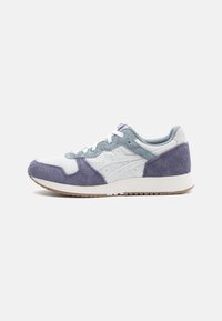 Fehér sneaker szürke és lila velúr részletekkel, textúrált hálós felsőrésszel, kerek orral, fehér fűzővel és gumitalppal. Diszkrét márkajelzés a sarkán.