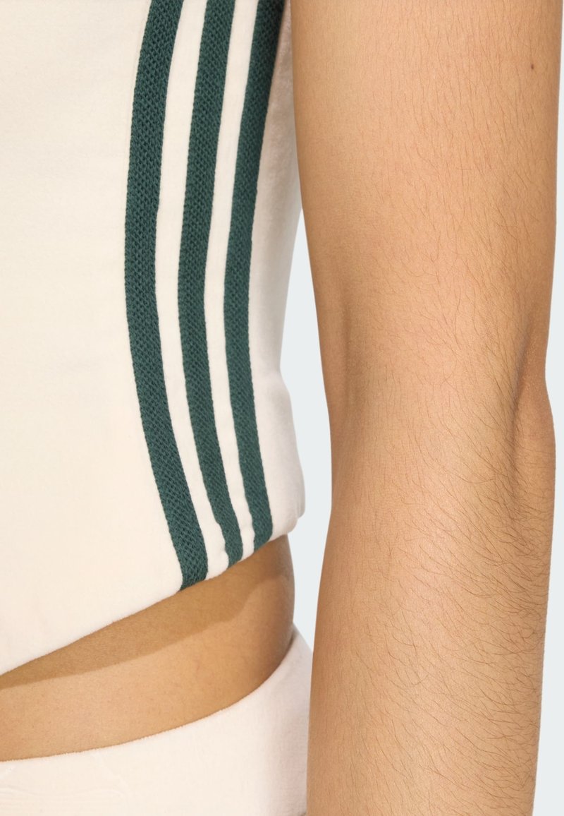 Romige cropped top met groene en witte gestreepte gebreide accenten op de mouwen, met een gladde textuur. Blootgestelde middengedeelte zichtbaar.